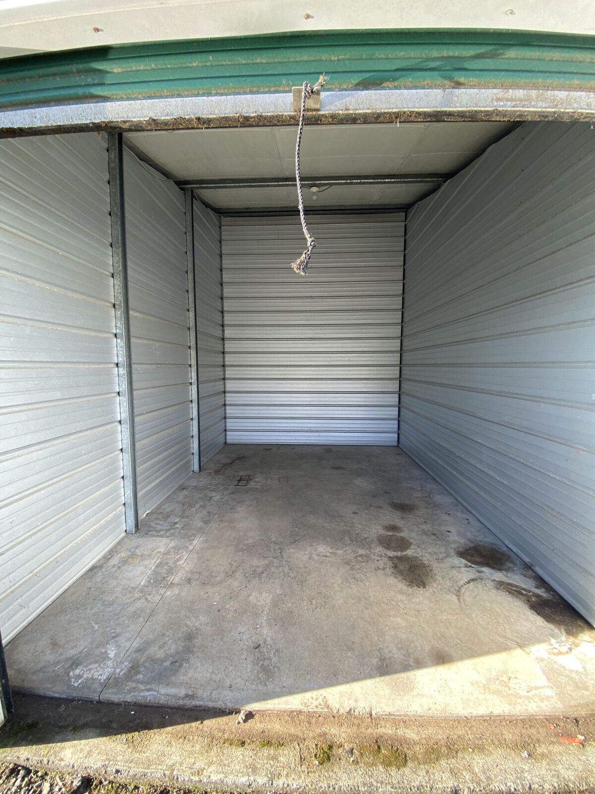 Clean, empty drive-up storage unit with metal walls and the roll-up door open
