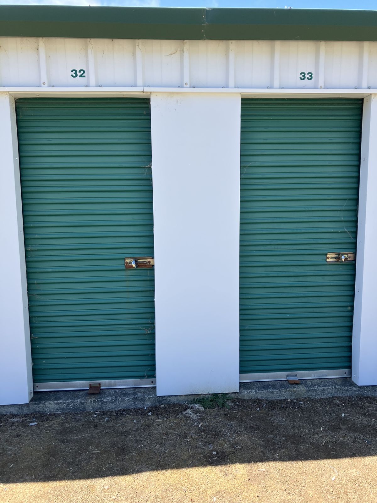 Two storage units with green roll-up doors